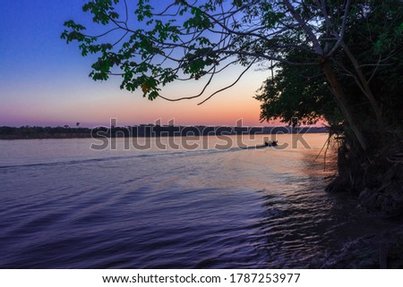 Sunset view of Las Piedras Rio (River) with a little wooden fishing boat, Puerto Maldonado, Peru