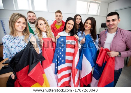 Group of young people holding international flags of many countries in the classroom, student exchange program