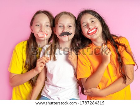 Happy Children hold fake mustache and lips on a pink background. Beauty salon.  Hair design salon. Salon photobooth.  Royalty-Free Stock Photo #1787264315