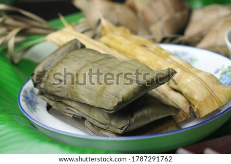 Buras, Indonesian traditional cake steam rice, wrapped with banana leaves. Served on ceramic plate with beef curry as condiment. Buras is one of popular food during hari raya Idul Fitri and Idul Adha. Royalty-Free Stock Photo #1787291762