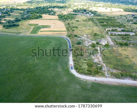 An asphalt road near a green corn field in Ukraine. Aerial drone view.