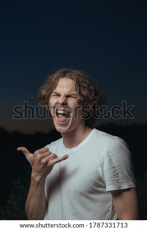 Cheerful guy shows a shak sign at sunset
