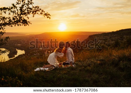 Romantic picnic of couple in love on mountain at gorgeous sunset. They kissing and feeling love. The concept of leisure, privacy, communication and vacation. Copy space. Royalty-Free Stock Photo #1787367086