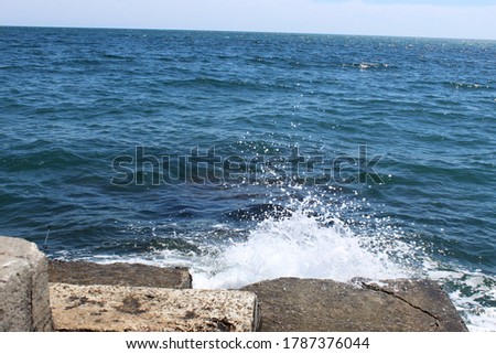 The crest of the sea wave. White foam waves on the sea surface. Rushing water in the sea. A wave hitting the dock