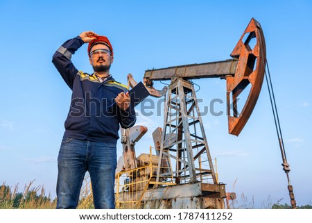 An engineer with a tablet in his hand checks the oil pumpers.