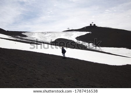 Capture the view of a tourist walking at the peak of Mount Etna