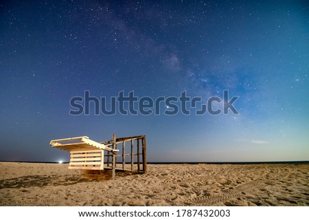 Milky Way core stretching across the night sky over a lifeguard tower on a beach. Long Island New York 