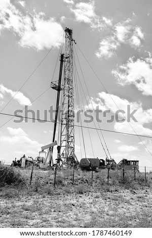 Small drilling oil rig platform in the farmland of West texas in black and white.
