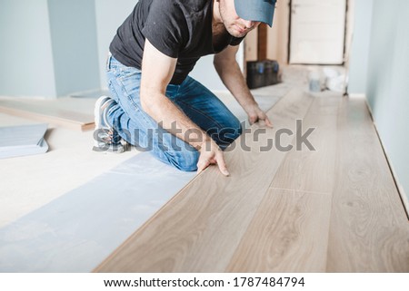 Close-up of the work of a master floating flooring installation - installing laminate on the floor - male hands during work Royalty-Free Stock Photo #1787484794