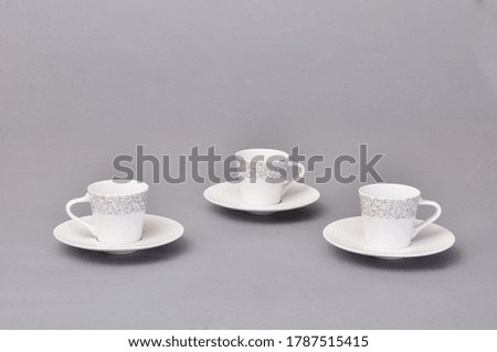 A set of coffee and tea cups, mugs and  plates on a gray background. 