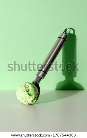 ice cream spoon with pistachio ice cream on pastel green background. Fashion Food Concept