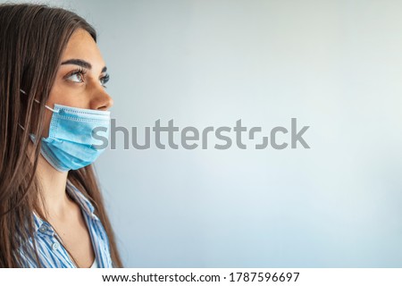 Young woman wears protective face mask, wrong way, incorrect wearing - masks should cover nose as well. How to NOT wear a mask. The wrong way to wear a mask on the chin and open nose