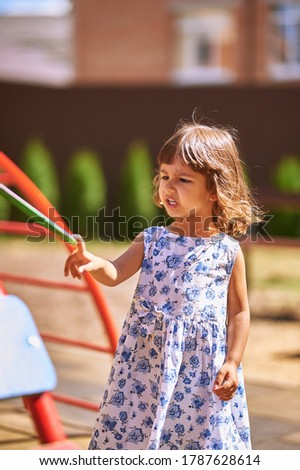 Little girl stands on the playground near the stairs for lasagna and something tells. High quality photo
