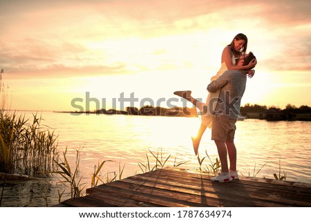 Enjoying By The River.Romantic smiling couple in love dating at sunset at river. Royalty-Free Stock Photo #1787634974
