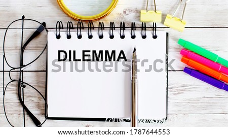 DILEMMA written in a notebook on white background with office tools