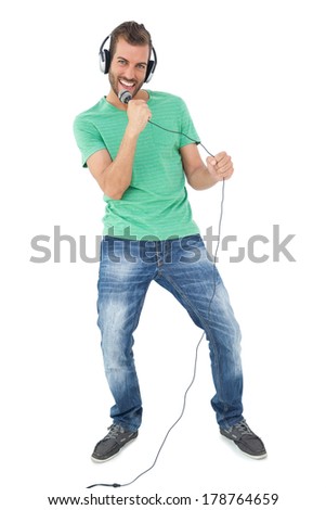 Portrait of a young man singing into microphone over white background