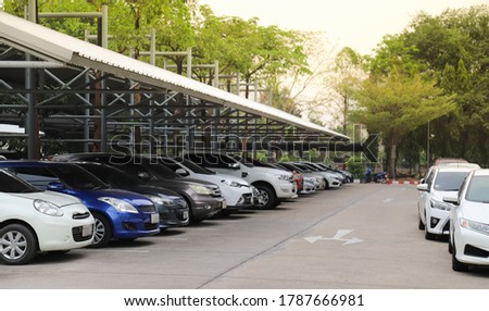 Closeup of front side of white car with other cars parking in indoor parking area with natural background in sunny day.