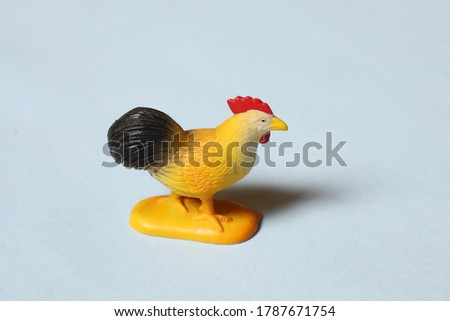 Toy farm rooster cock figurine on blue background 