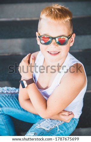 blond boy in a white t-shirt with hearts on dark glasses.