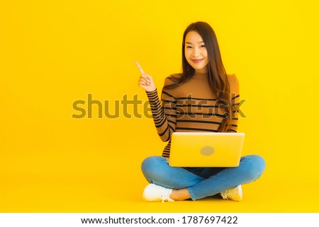 Portrait beautiful young asian woman sit on the floor for use laptop or computer on yellow isolated background