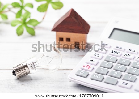 Miniature bulb and calculator on white board Royalty-Free Stock Photo #1787709011