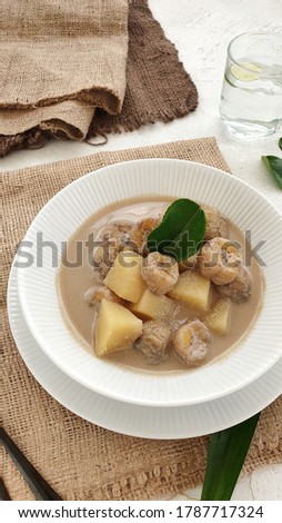 A bowl of Kolak in white background. Kolak is an Indonesian dessert based on palm sugar or coconut sugar, coconut milk, and pandanus leaf contains banana and sweet potatoes. Copy space. Isolated