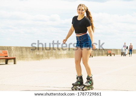 Happy joyful young woman wearing roller skates relaxing after long ride. Female being sporty having fun during summer time on pier