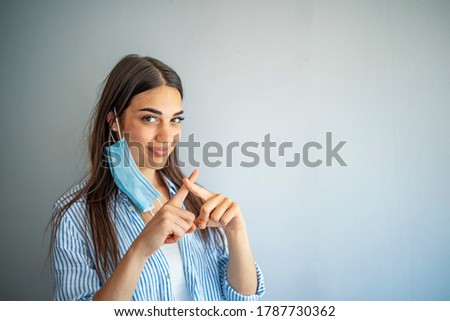 The woman show the wrong way to wear Hygienic mask. The girl incorrectly put on a protective mask. Protection from disease and virus. Disposable mask. Self-isolation protection. The woman smiles. Royalty-Free Stock Photo #1787730362
