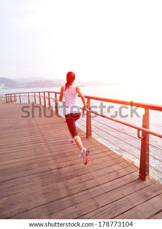 healthy lifestyle sports woman running on wooden trail seaside