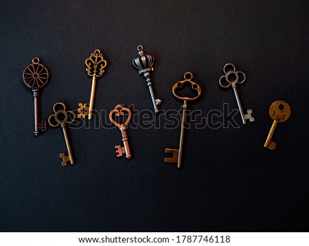 Many different old keys from different locks, scattered chaotically, flat lay. Finding the right key, encryption, concept. Retro vintage copper keys in black background