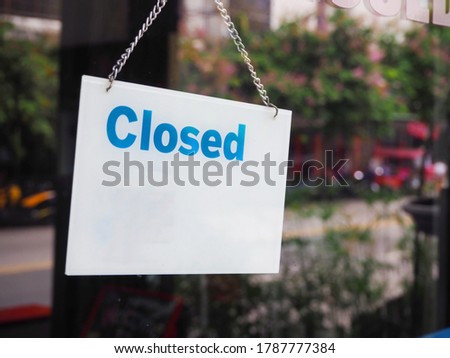 close up of closed sign in front of glass windows shop store at downtown