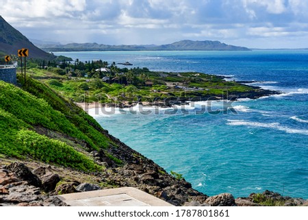 A rocky beach next to a body of water in Hawaii. A beautiful landscape of Oahu's beach and mountains. High quality photo