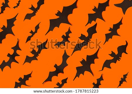 decoration concept for Halloween.  Black paper bats fly in one directions on an orange background.  template