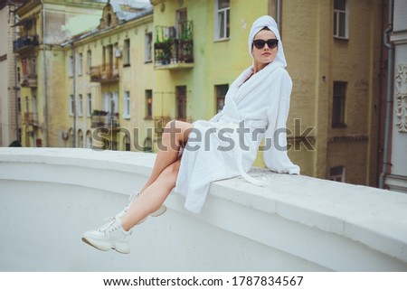Beautiful young smiling girl in a white robe on the balcony