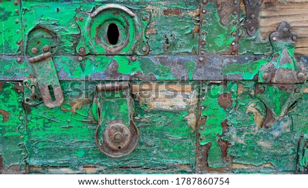 Close up of an old wooden crate painted green with a rusty lock