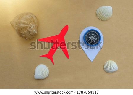 The plane, a sign of geolocation, compass, sea shells on a light brown background. Travel, recreation, resort. holidays.