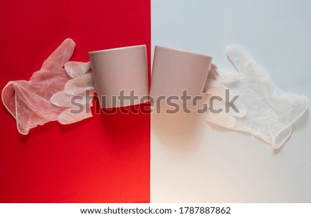 cheers with a cup of coffee. The picture shows coffee cups and the gloves on red and white background.