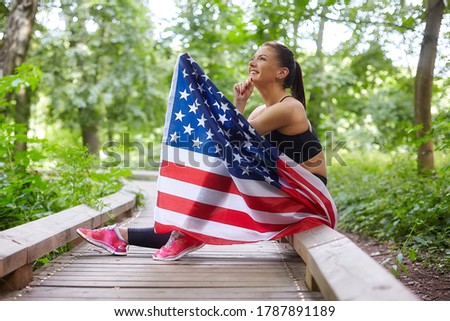 attractive woman posing with american flag in forest park