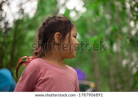 Girl 4 years old in the forest. Little girl of Asian appearance. The child walks in the summer. Portrait in natural light. Joyful emotions on the face of the child.