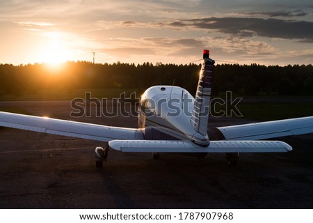 Quadruple aircraft parked at a private airfield. Rear view of a plane with a propeller on a sunset background. Royalty-Free Stock Photo #1787907968