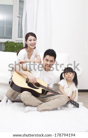 	Young family playing guitar in living room	