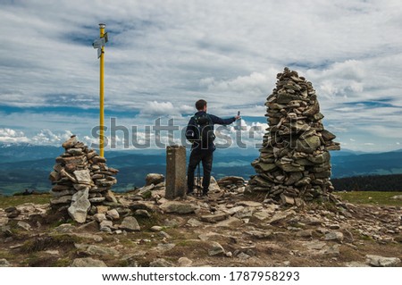 Man takes a selfie on the top of Pilsko Beskid Zywiecki, border Poland - Slovakia. Mysterious stone cairn in the mountains.