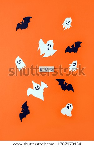 Word Boo. Wooden blocks with lettering on orange background decorated with bats and ghosts from cardboard. Vertical postcard, top view