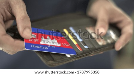 Man pulls plastic bank card with flag of Cambodia out of his wallet, fictional card number
