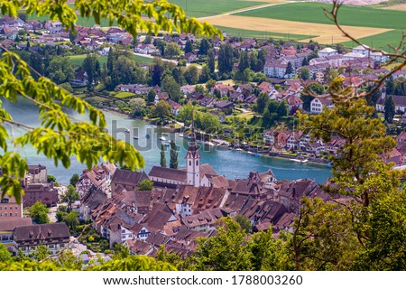 A hilltop aerial view of the scenic historical town Stein am Rhein on the banks of Rhine river in Switzerland. Image features rooftops of vintage houses as well as the tower of the  St. George's Abbey