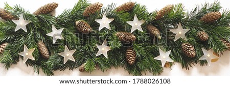 Screensaver or greeting card. White wooden background with lined natural spruce branches, fir cones and lamps of white matte stars.