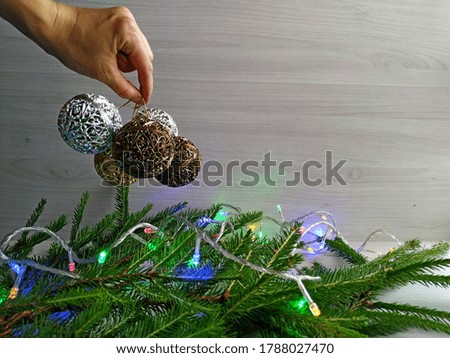 decorate the Christmas tree: Christmas garland and golden carved balls. Woman's hand holds golden and silver carved balls to decorate the christmas tree