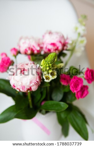 A beautiful bouquet of tender pink peonies and small roses stands on a white chair. Wedding bouquet, birthday. Close-up