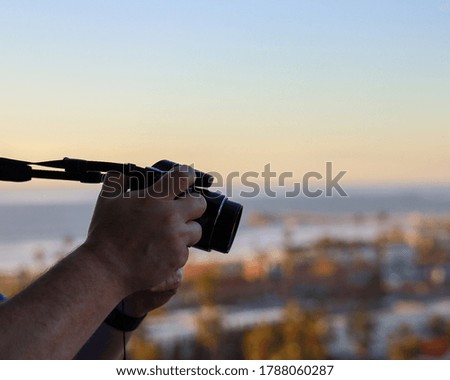 View of a male's hands holding a camera while taking a picture.