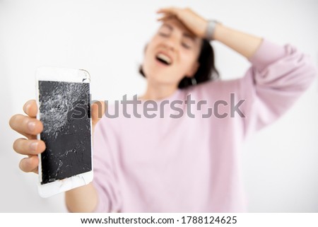 Broken glass of phone screen in hands of young woman, white background.